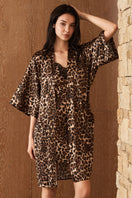 Woman wearing a luxurious leopard print silk robe by MANITO, featuring a jungle-inspired leopard pattern.