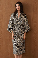 Woman wearing a jungle zebra print silk robe by MANITO, featuring a stylish zebra pattern and luxurious silky fabric.