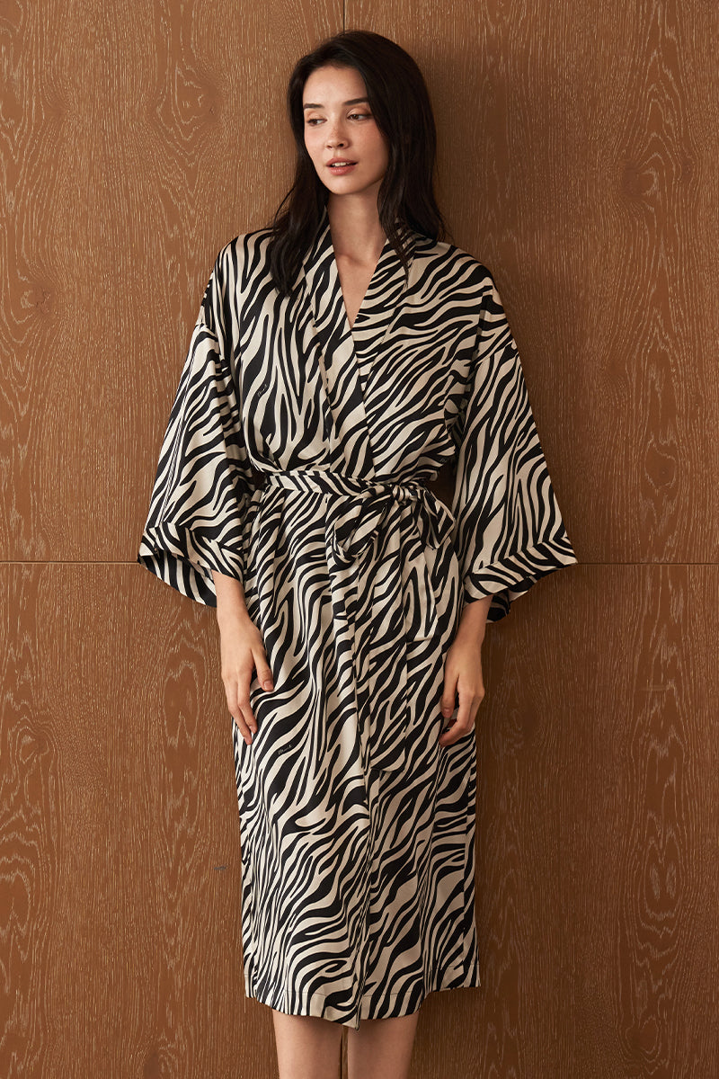 Woman wearing a jungle zebra print silk robe by MANITO, featuring a stylish zebra pattern and luxurious silky fabric.
