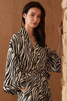 Woman wearing MANITO jungle zebra print silk robe with bold zebra pattern, flowing fabric, and relaxed fit.