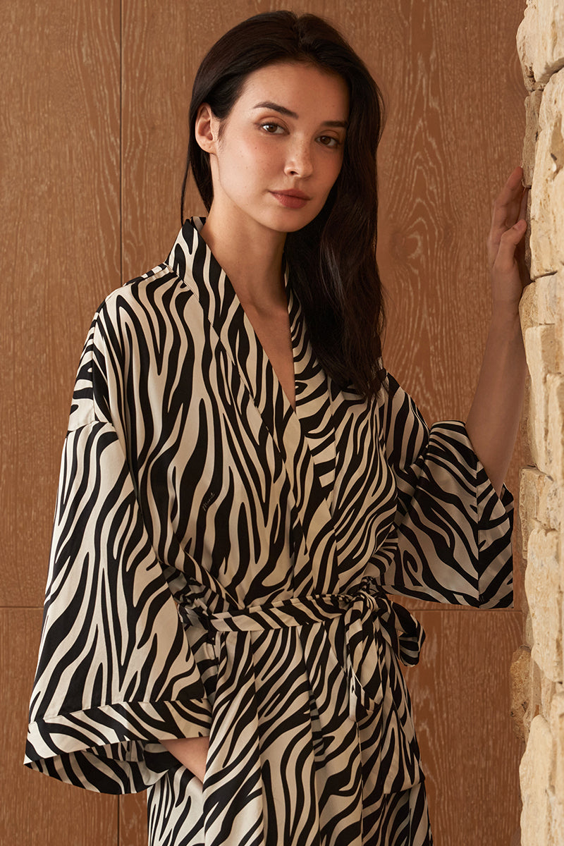 Woman wearing MANITO jungle zebra print silk robe with bold zebra pattern, flowing fabric, and relaxed fit.