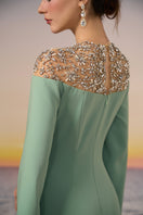 Mint Calypso crepe gown by 21Six displayed on a hanger, showcasing its elegant design and flowing fabric.