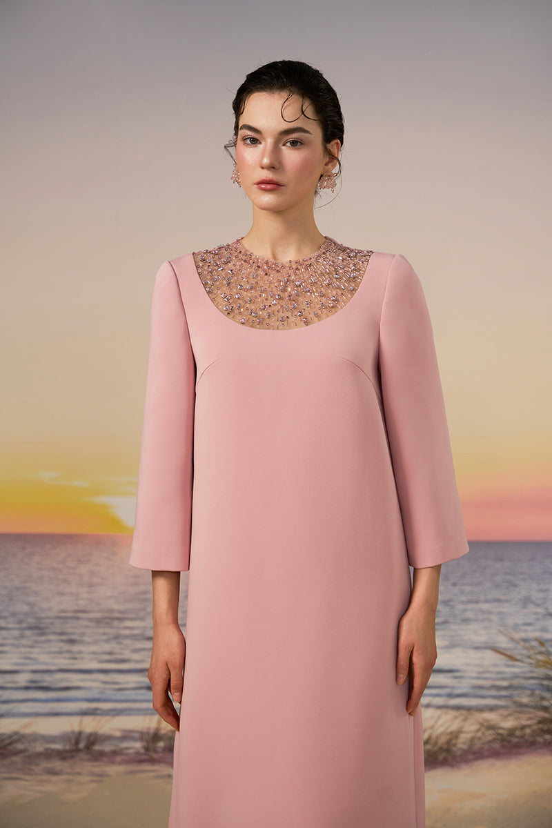 Light rose EIRA crepe gown by 21Six, featuring a flowing silhouette and elegant design, displayed on a hanger against a neutral background.