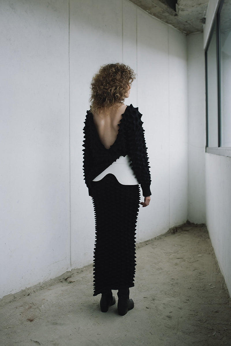 Black knitted co-ord set by MAZ Manuela Álvarez featuring a sweater and matching skirt, styled for a cozy, chic look.