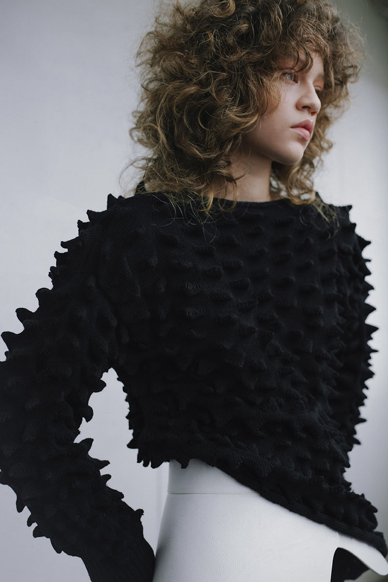 Black knitted co-ord set featuring a fitted sweater and matching skirt by MAZ Manuela Álvarez, styled for a chic, casual look.