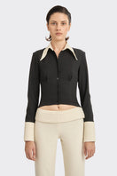 Black Kaia shirt by Stolen Stores featuring a stylish top with white accents, displayed on a hanger against a plain background.