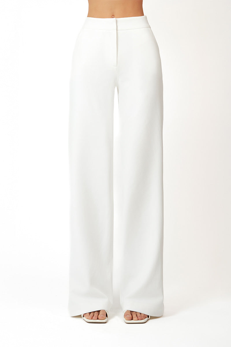 White Khanum's pants with a relaxed fit, shown hanging on a wooden hanger against a neutral background.
