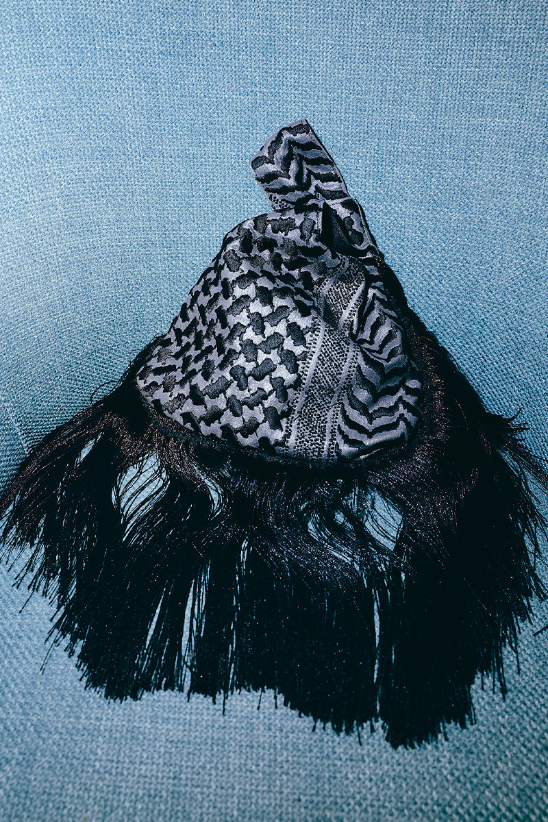 Black keffiyeh slip clutch bag with fringes by Sarah's Bag, featuring a textured fabric and sleek design.