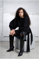 Black knitted sweater with long braids from MAZ Manuela Álvarez, featuring a cozy, textured knit design and long braided details.