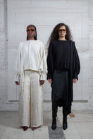 Black knitted sweater with long braid details from MAZ Manuela Álvarez, featuring cozy textured knit and stylish long braid accents.