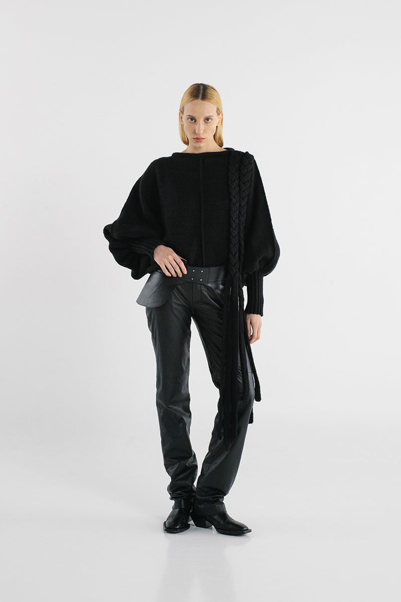 Black knitted sweater with long braided details from MAZ Manuela Álvarez, featuring cozy, textured knit fabric.