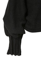 Black knitted sweater with long braids from MAZ Manuela Álvarez, featuring intricate knit pattern and cozy long sleeves.