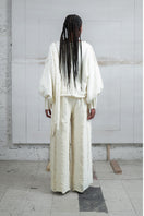 Ivory knitted sweater with long braids by MAZ Manuela Álvarez, featuring a cozy, textured design and long sleeve details.