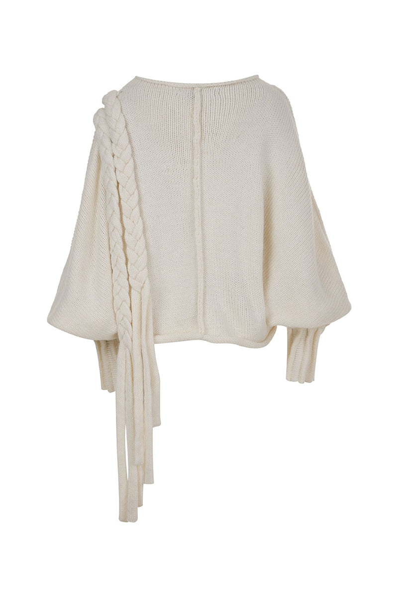 Ivory knitted sweater with long braids by MAZ Manuela Álvarez, featuring a cozy, textured design and long braided accents.