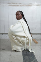 Ivory knitted sweater with long braids by MAZ Manuela Álvarez, featuring a cozy, textured design and long braided details.