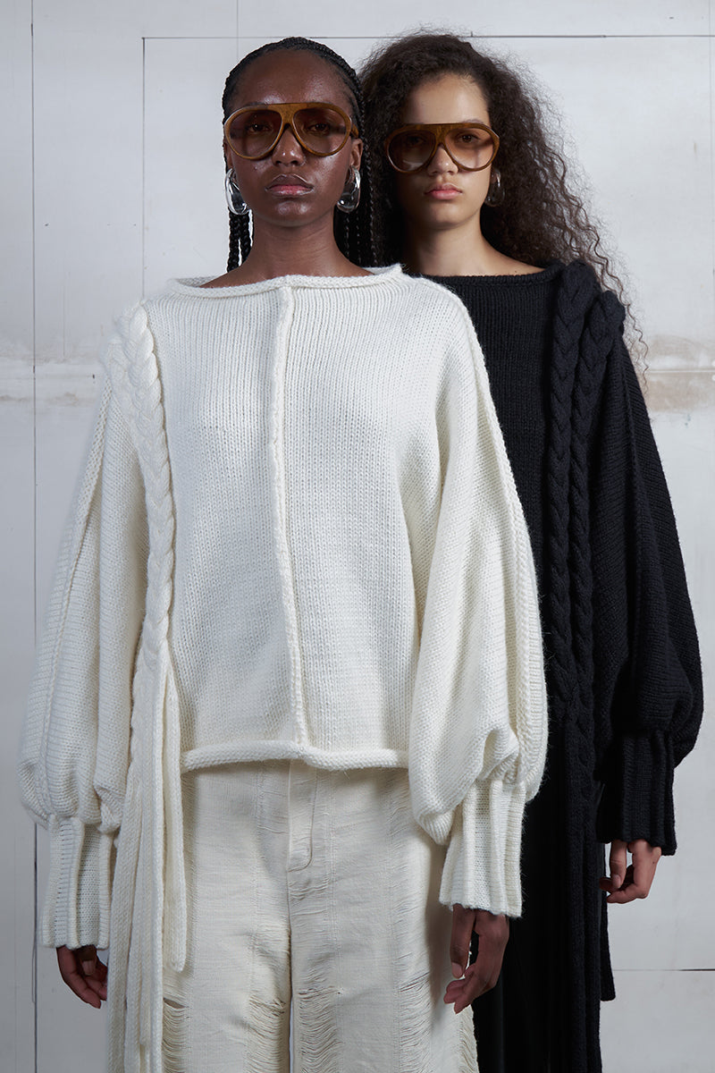 Ivory knitted sweater with long braids from MAZ Manuela Álvarez, featuring a cozy, textured knit design and long braided details.
