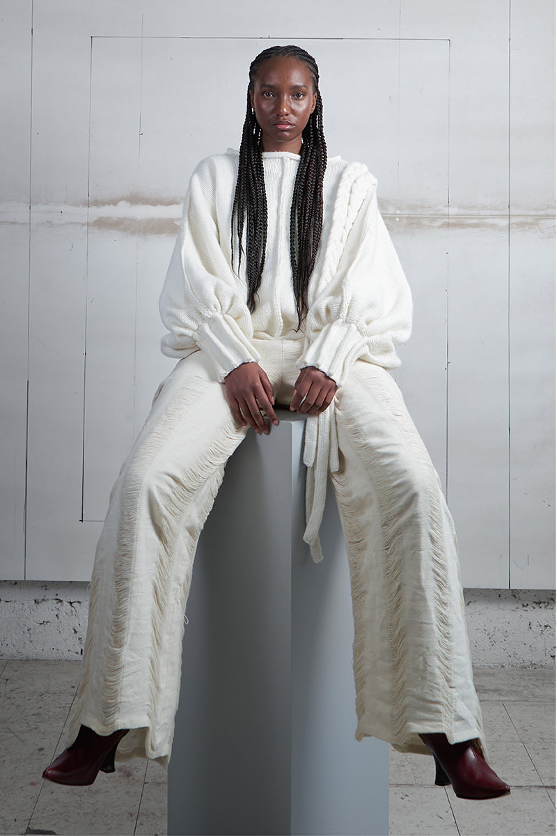 Ivory knitted sweater with long braided details by MAZ Manuela Álvarez, featuring a cozy, textured design for casual wear.