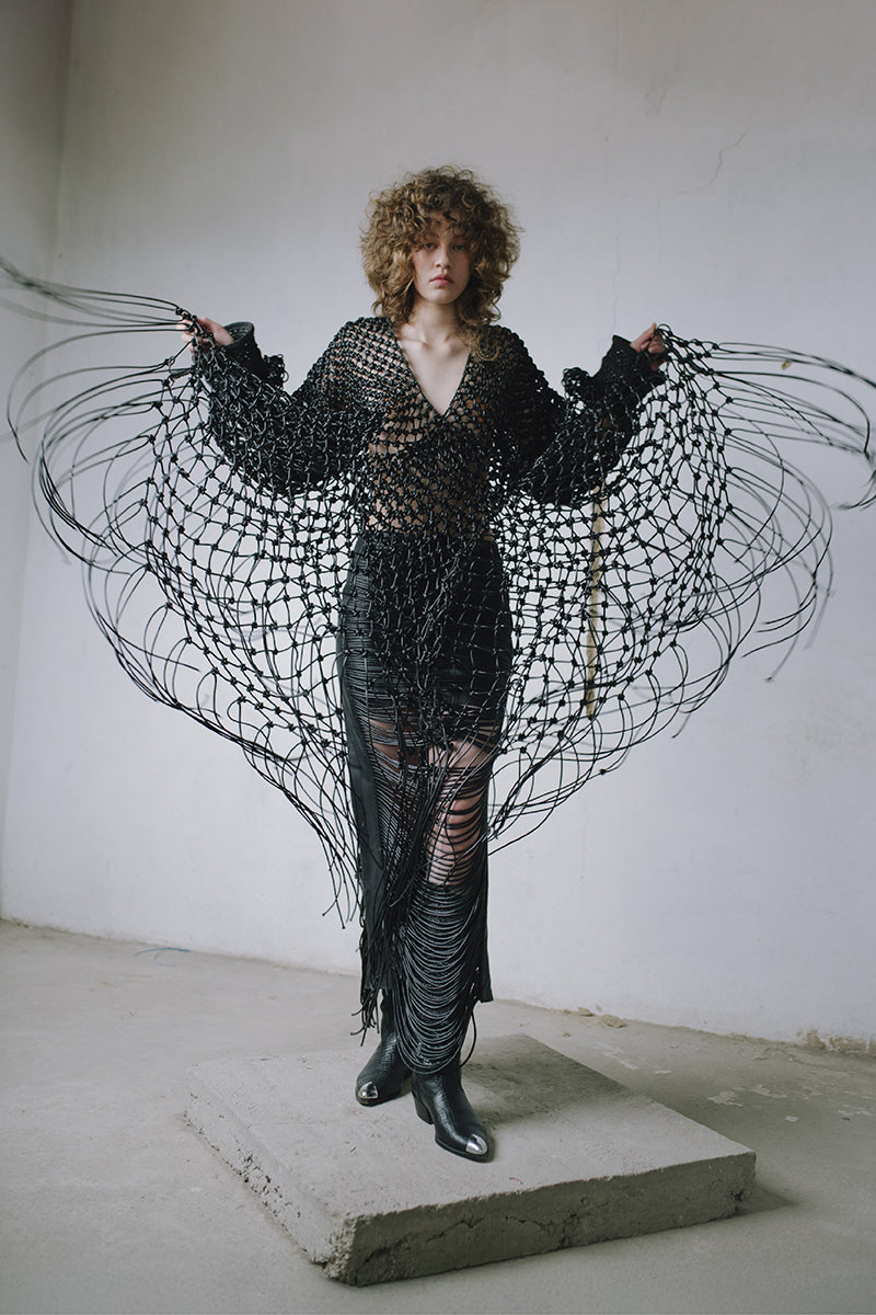Black leather snake-like cord maxi skirt by MAZ Manuela Álvarez, featuring a sleek, textured design and flowing length.