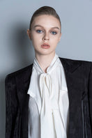 Black LEKIEU Grenoble jacket with a sleek design, shown hanging on a wooden hanger on a white background.