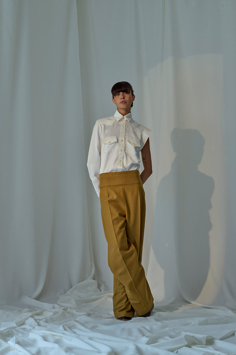 Light-colored Isabela blouse by Lorena Saravia, featuring stylish design details, displayed on a hanger against a neutral background.