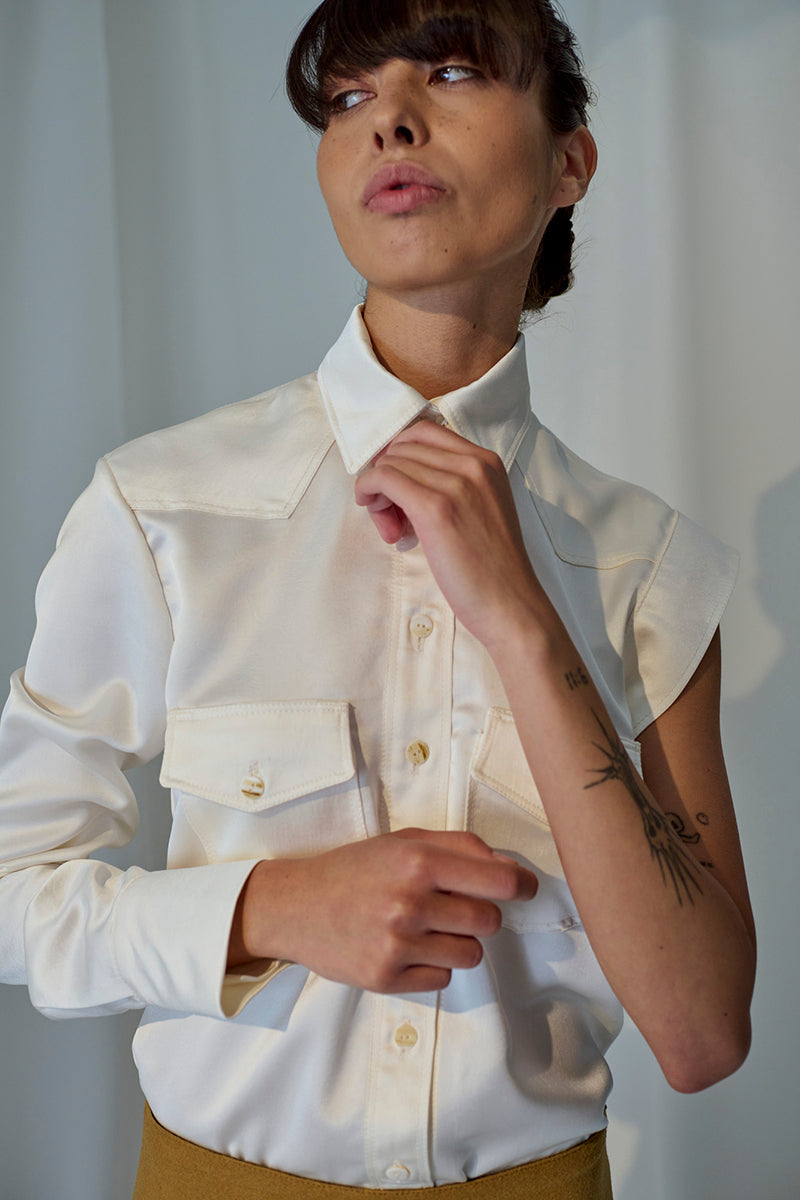 Lorena Saravia Isabela blouse, stylish shirt with intricate details, displayed on a hanger against a neutral background.