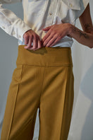 Lorena Saravia Serena wool pants in neutral color, tailored fit, front pockets, and wide-leg design, displayed on a hanger.