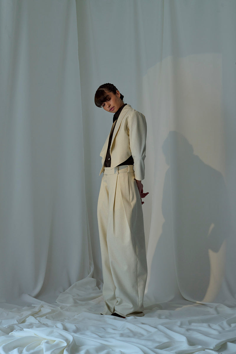Lorena Saravia Alex wool pants in neutral fabric, tailored fit with front pockets, displayed on a model.