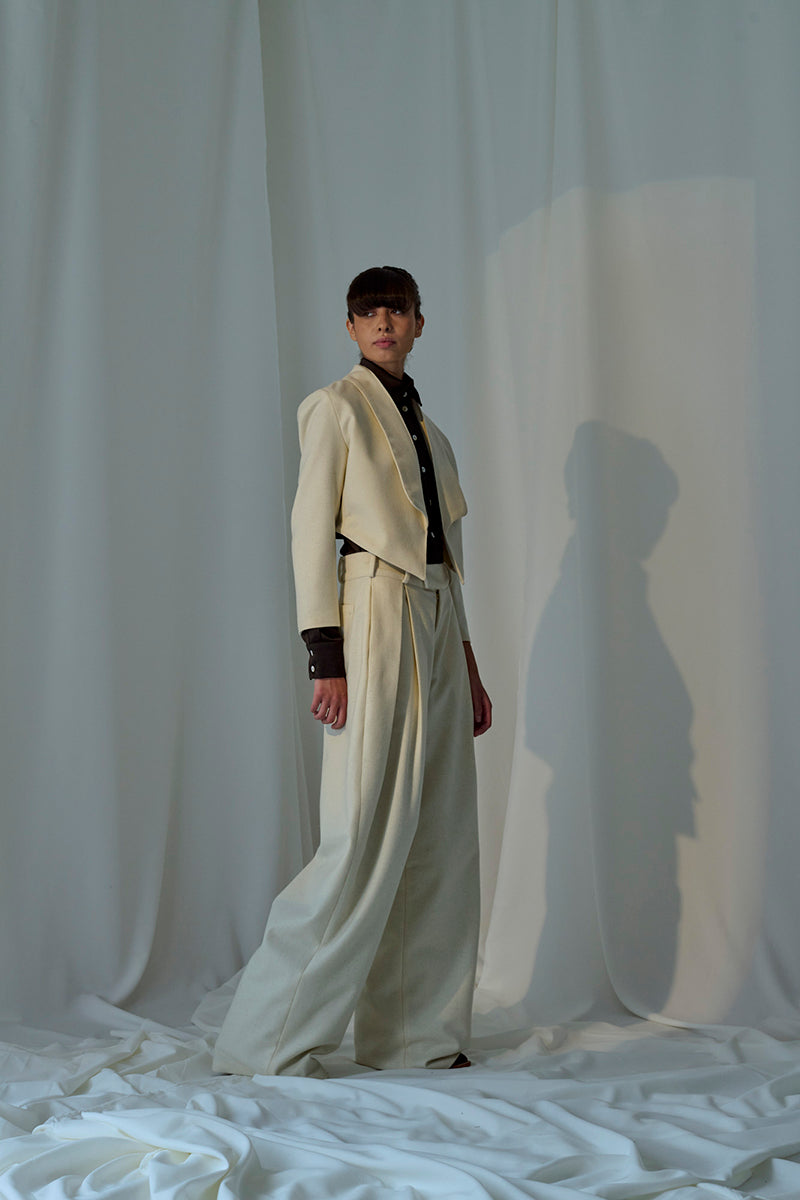 Lorena Saravia Alex wool pants in neutral color, tailored fit, with side pockets and waistband, displayed on a hanger.