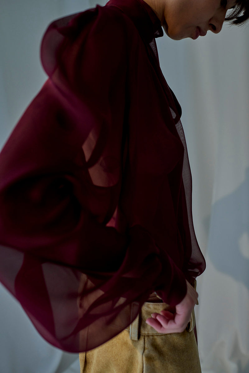 Lorena Saravia Natalia blouse, stylish women's top with elegant design, shown on a hanger in a fashion photoshoot.