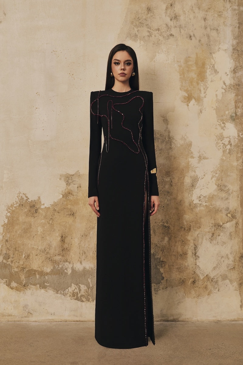 Black long-sleeve maxi dress with heart beading front slit from L'SCARLETT, featuring elegant design and flowing fabric.