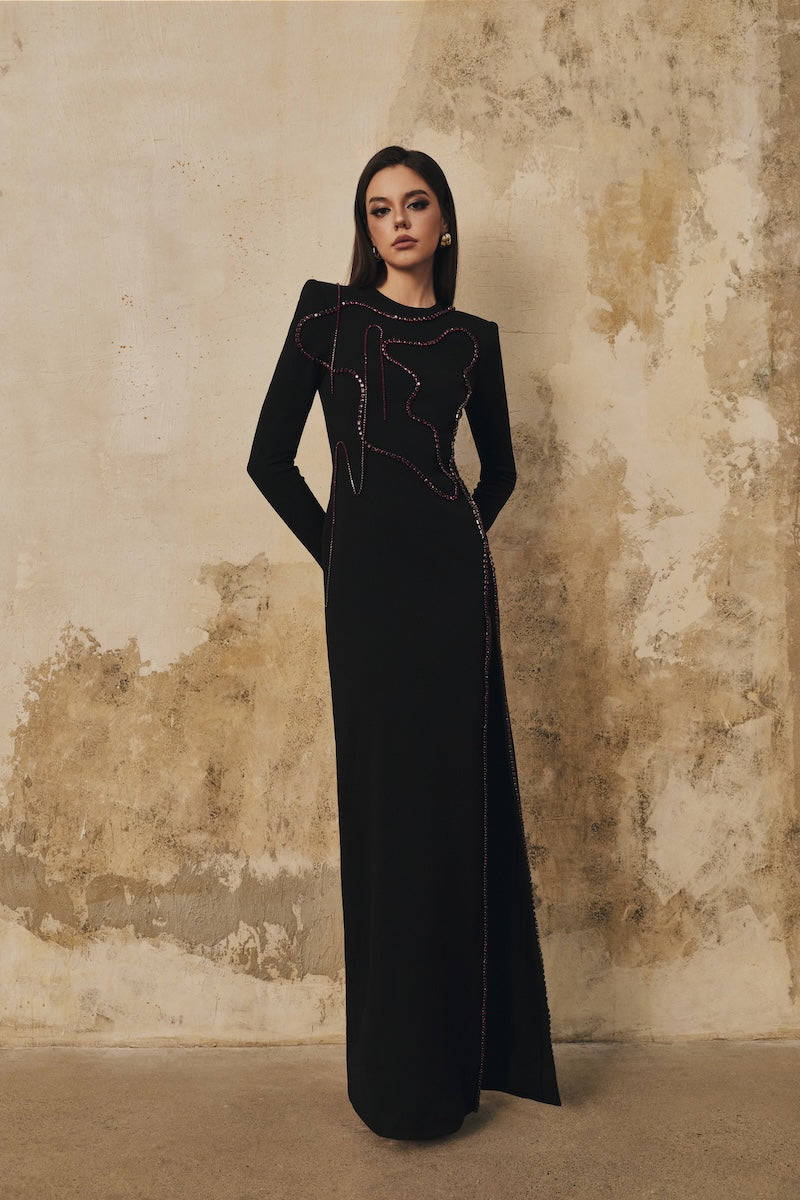 Black long-sleeve maxi dress with heart beading detail and front slit from L'SCARLETT, featuring a fitted silhouette and elegant design.