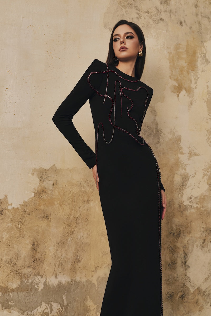Black long-sleeve maxi dress with heart beading front slit by L'SCARLETT, featuring a fitted silhouette and elegant design.