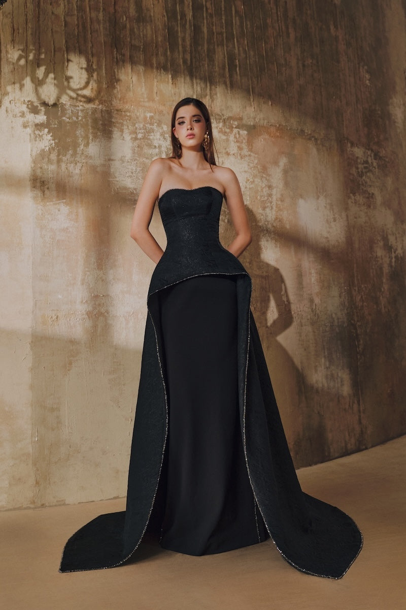 Black strapless floor-sweeping maxi dress with a mullet overskirt by L'SCARLETT, elegant and flowing for formal occasions.