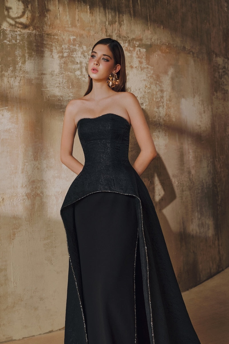 Black strapless floor-sweeping mullet overskirt maxi dress by L'SCARLETT, shown with flowing fabric and elegant silhouette.