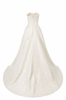 White strapless floor-sweeping mullet overskirt gown by L'SCARLETT, shown from the back with flowing fabric and elegant fit.