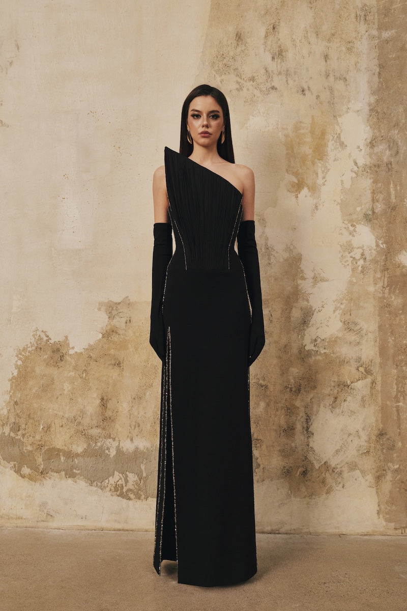 Black L'SCARLETT maxi dress with pointed bustline, crystal beading details, and front slit, perfect for elegant occasions.