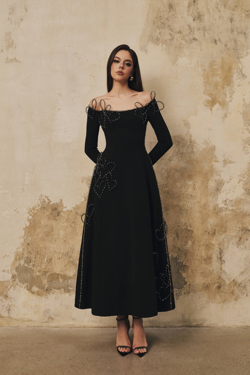 Black flared off-shoulder long-sleeve midi dress with heart beading from L'SCARLETT, featuring a fitted bodice and flowing skirt.