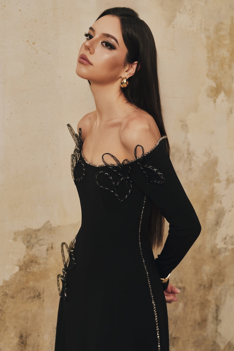 Black L'SCARLETT flared off-shoulder long-sleeve midi dress with heart beading detail, elegant and stylish for special occasions.