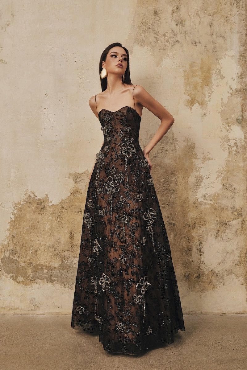 Black A-line spaghetti-strap maxi dress with 3D crystal floral embellishments by L'SCARLETT, featuring elegant flowing fabric.