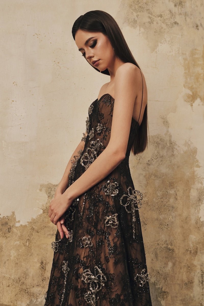 Black A-line spaghetti-strap maxi dress with 3D crystal floral details by L'SCARLETT, elegant and flowing for special occasions.