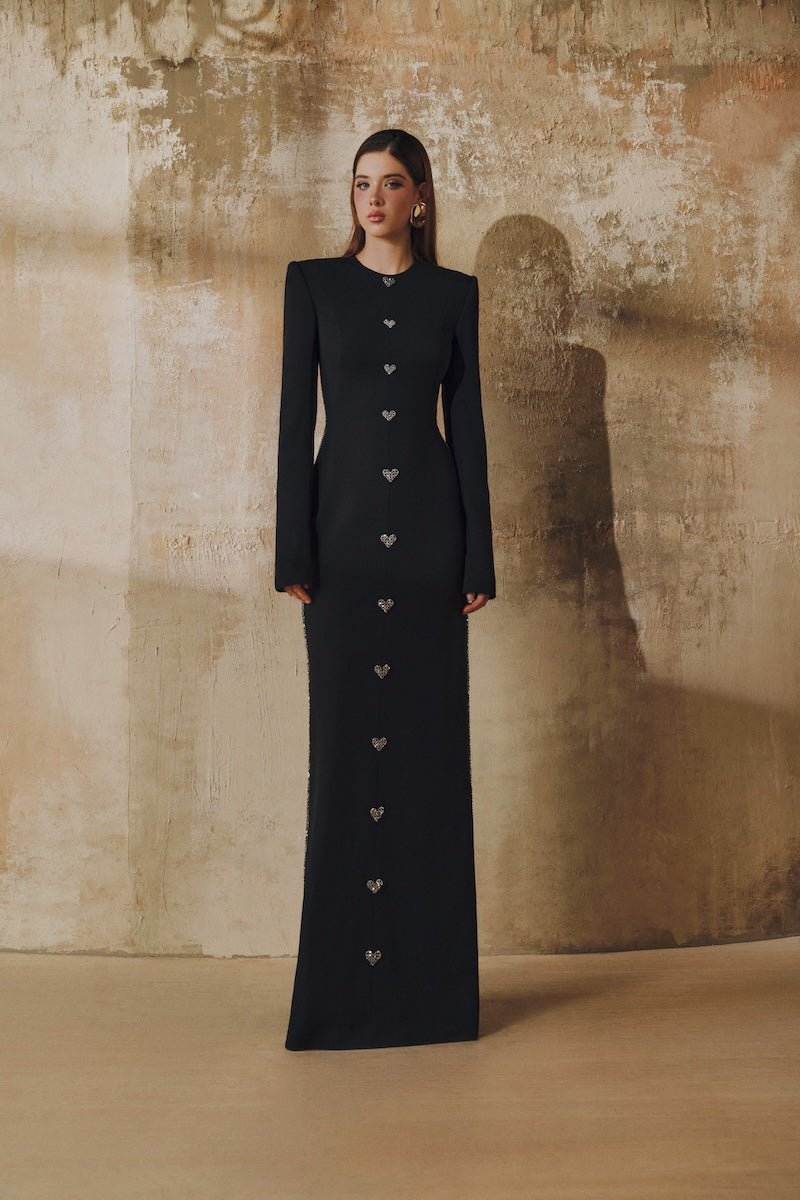 Black L'SCARLETT maxi dress with straight cut, long sleeves, hand-embellished crystal heart design, perfect for elegant occasions.