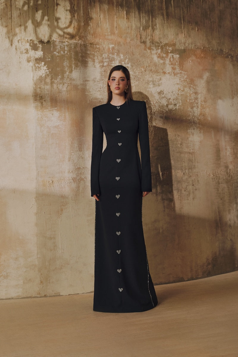 Black L'SCARLETT maxi dress with straight cut, long sleeves, hand-embellished crystal heart design, elegant evening wear.