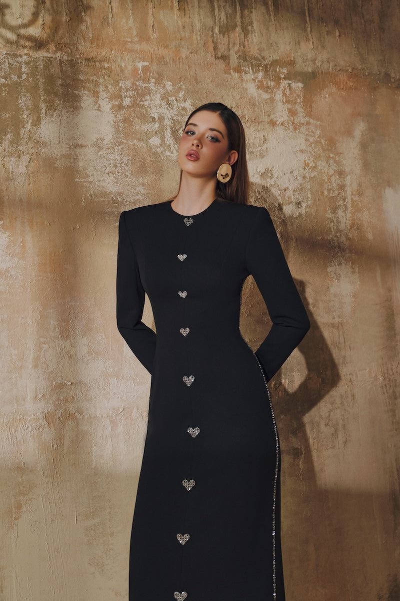 Black L'SCARLETT maxi dress with straight cut, long sleeves, and hand-embellished crystal heart design.
