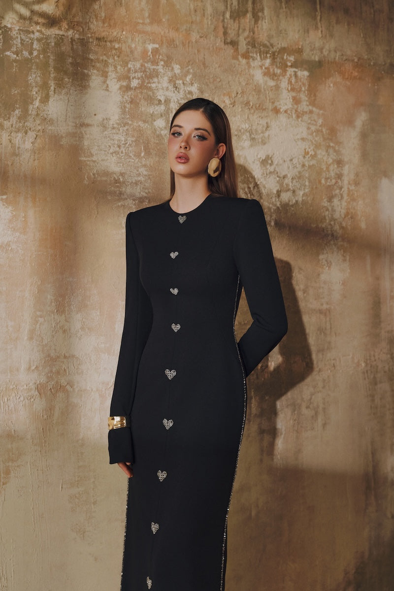 Black L'SCARLETT maxi dress with straight cut, long sleeves, hand-embellished crystal heart detail, elegant evening wear.