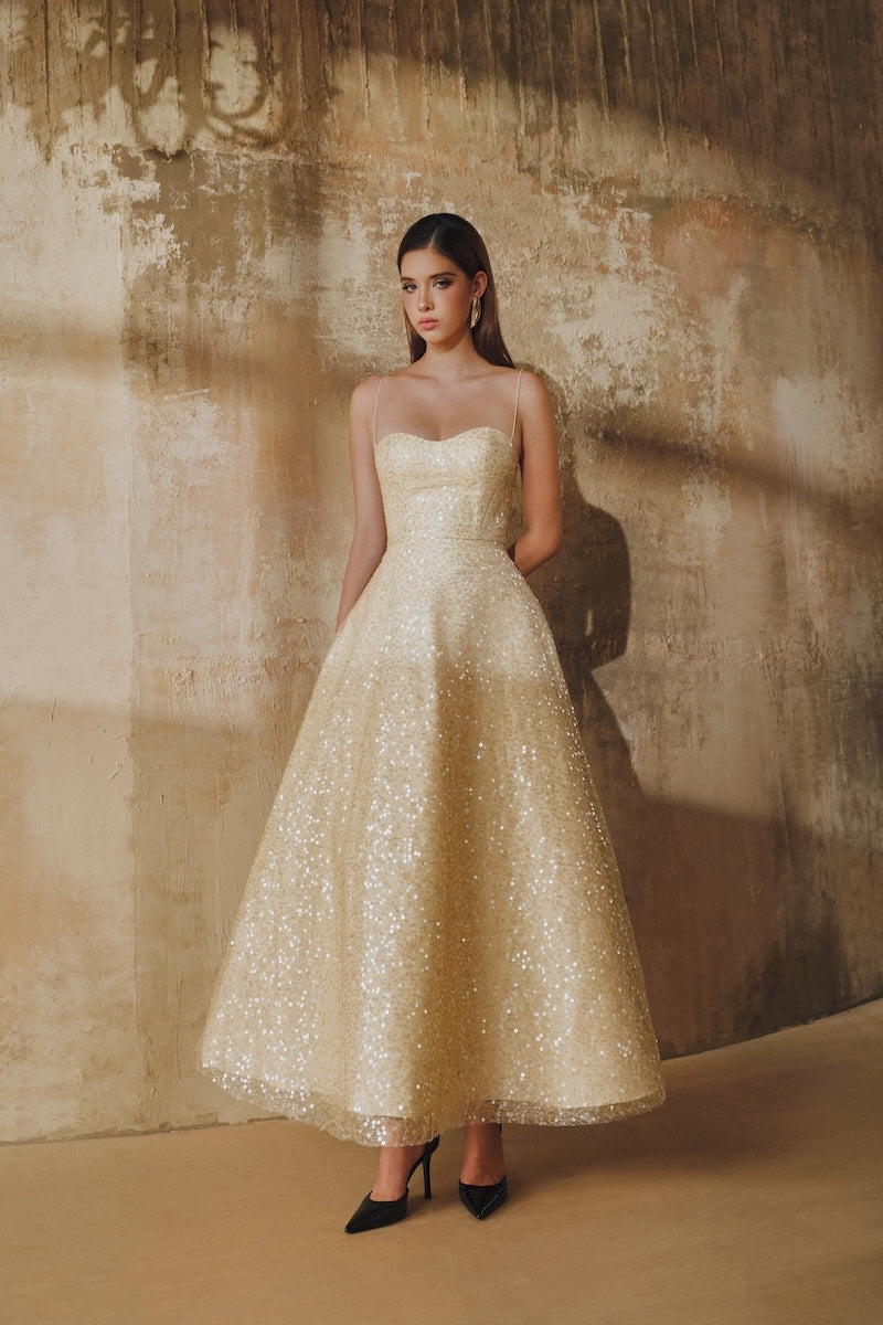 Light gold L'SCARLETT flared spaghetti-strap sequin midi dress displayed on a hanger.