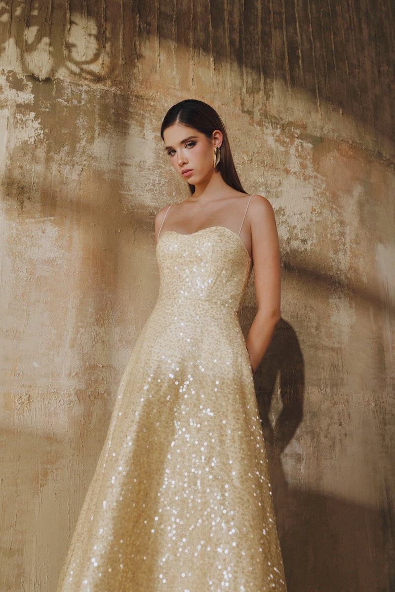 Light gold flared spaghetti-strap sequin midi dress by L'Scarlett, featuring a fitted bodice and flowing skirt.