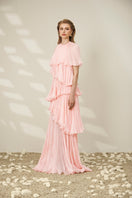 Pink tiered gown by Le Thanh Hoa featuring flowing fabric and elegant design, perfect for formal occasions.