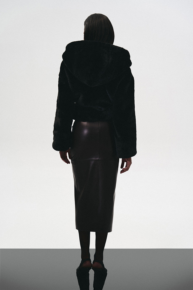 Black hooded fur jacket with cutouts by Kris Marán, showcasing a stylish, layered design with textured fur details.