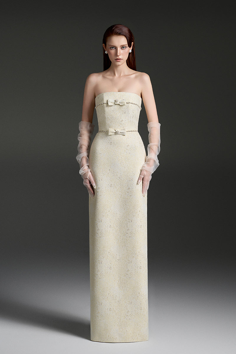 Light yellow strapless lacquered brocade gown by I.H.F Studio with pearl and crystal chain embellishments.