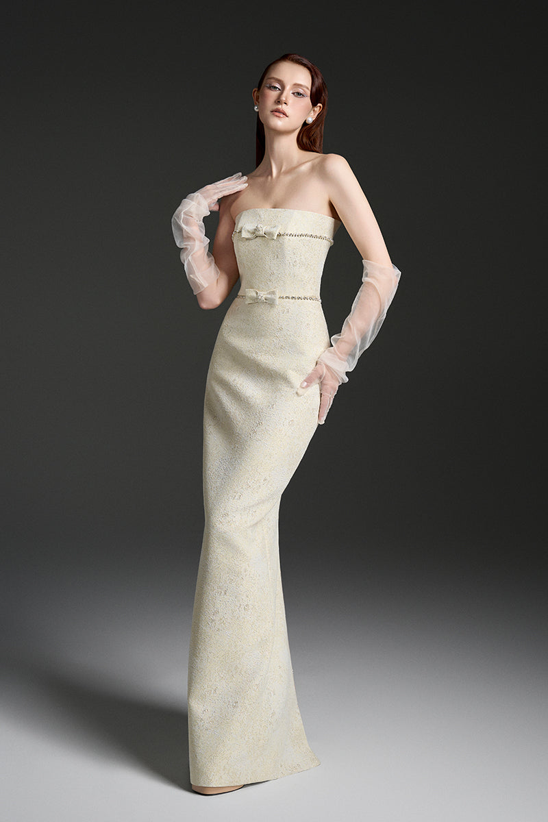Light yellow strapless lacquered brocade gown by I.H.F Studio featuring pearl and crystal chain embellishments.